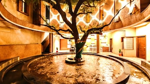 A courtyard with a central fountain, surrounded by a building with multiple windows and doors. - Hotel Malligi (Hospet)