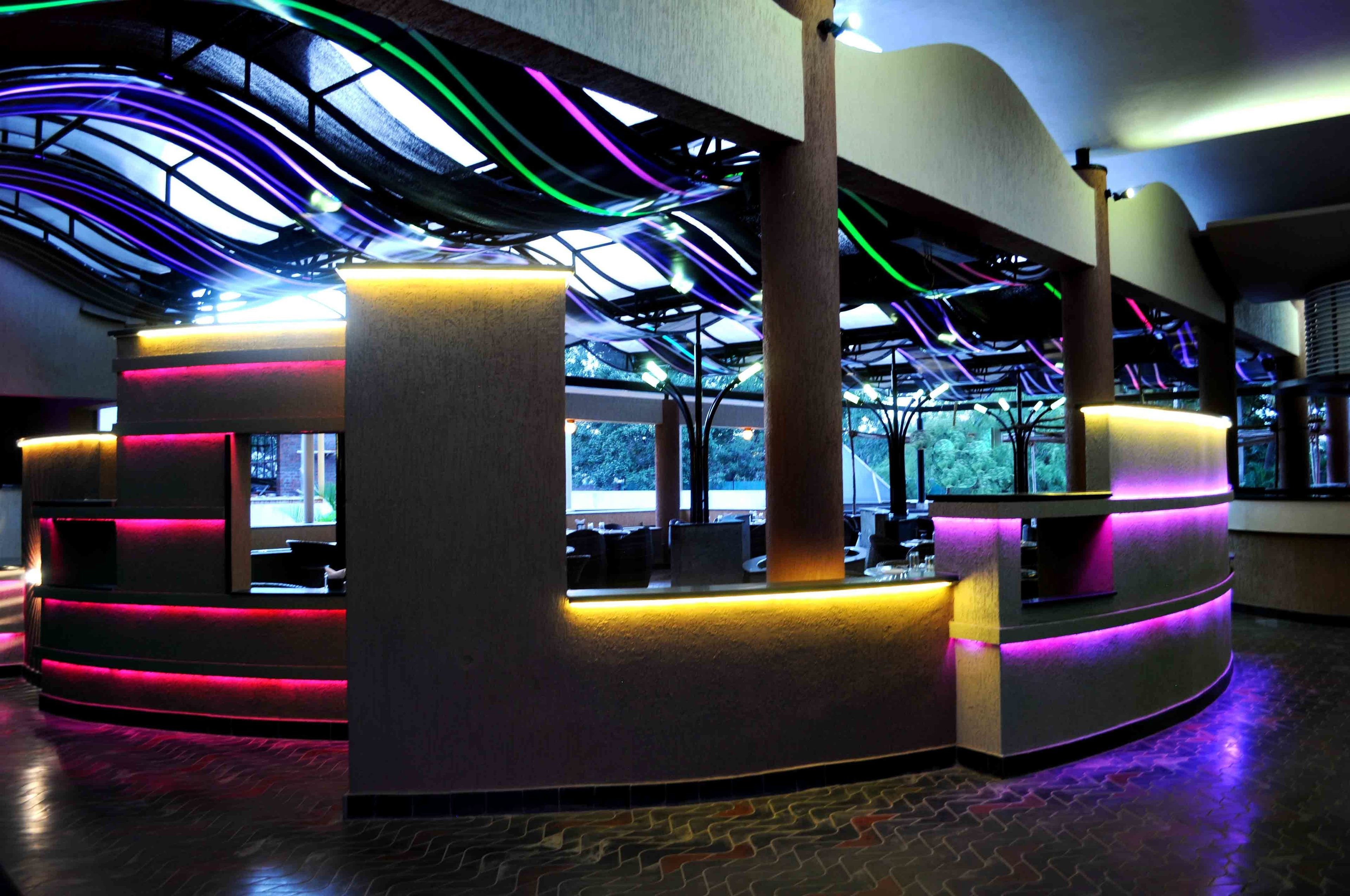 Un espace d’accueil moderne doté d’un comptoir incurvé, de grandes fenêtres et d’un plafond éclairé de couleurs vives.