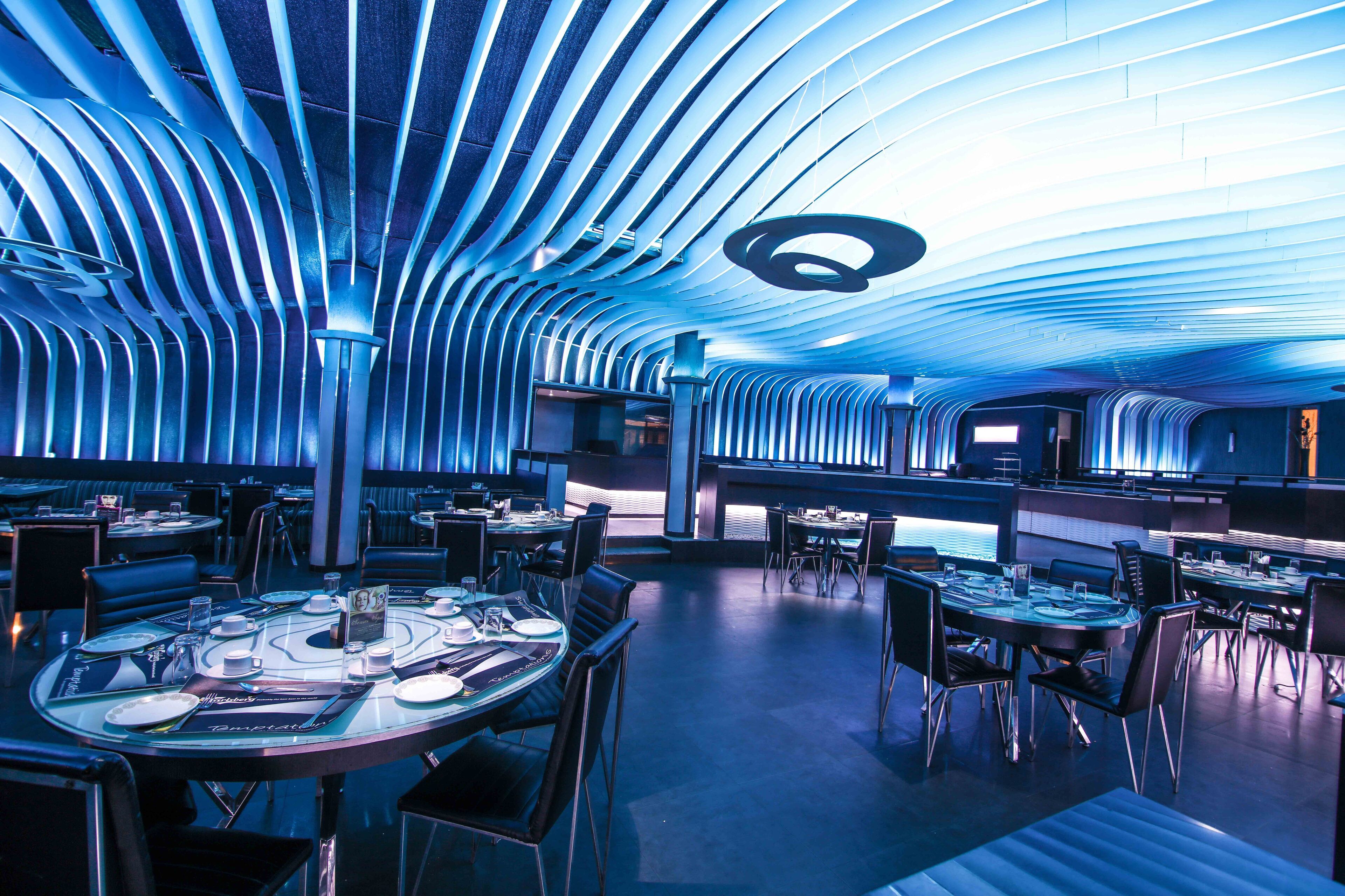 En moderne restaurant med et unikt loftdesign, flere spiseborde og stole.