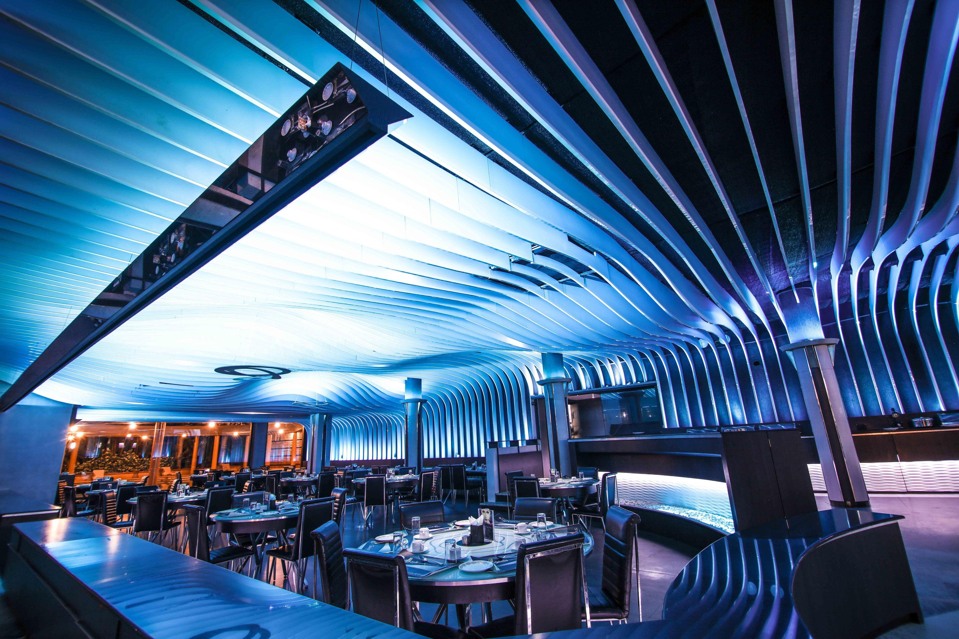 A modern restaurant with a curved ceiling and multiple dining tables.