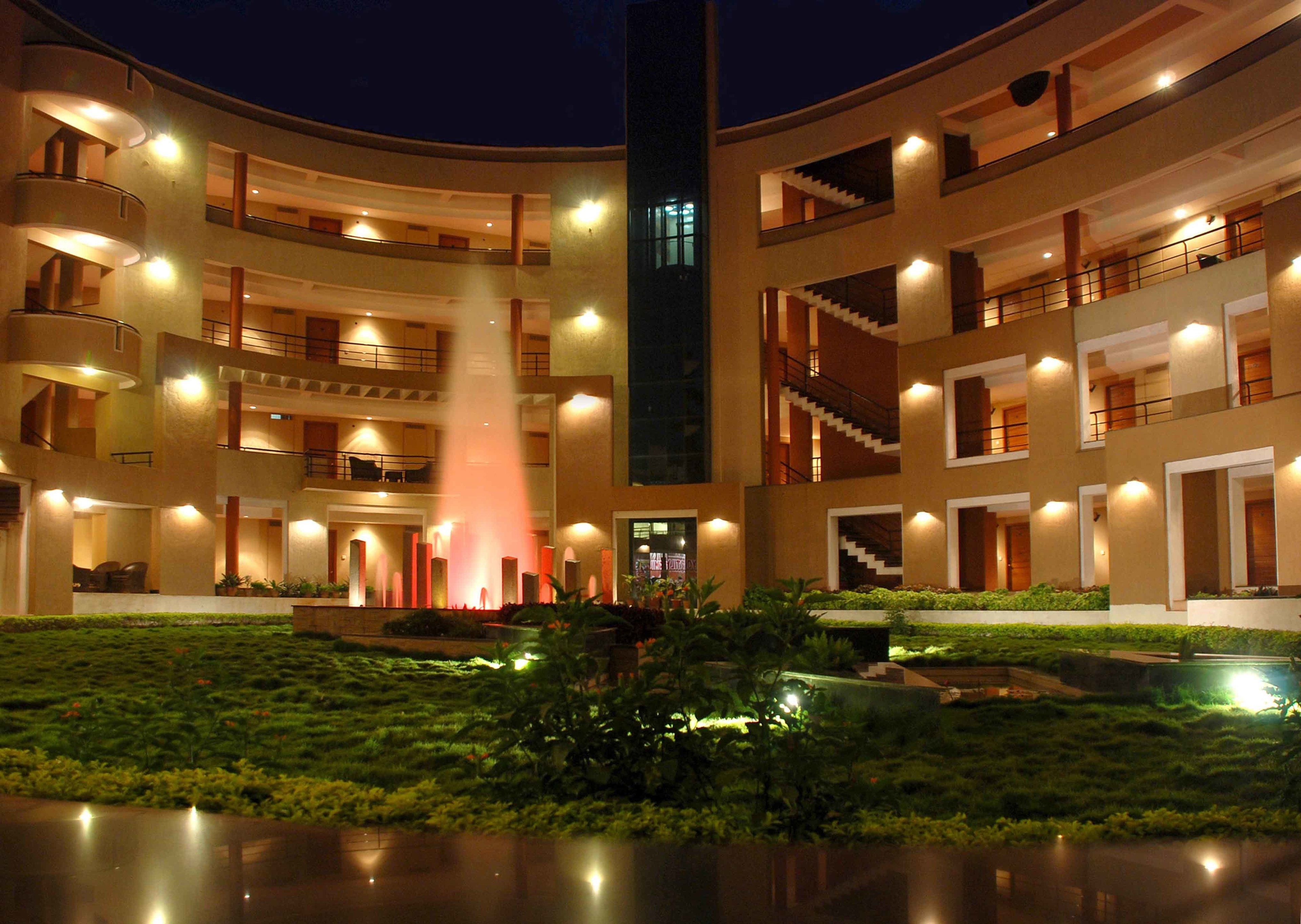Un hotel de varios pisos con una fuente central, balcones e un patio bien iluminado.