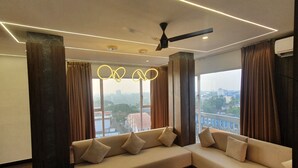 A modern living room with a sectional sofa, a round coffee table, and a view of the city through large windows.