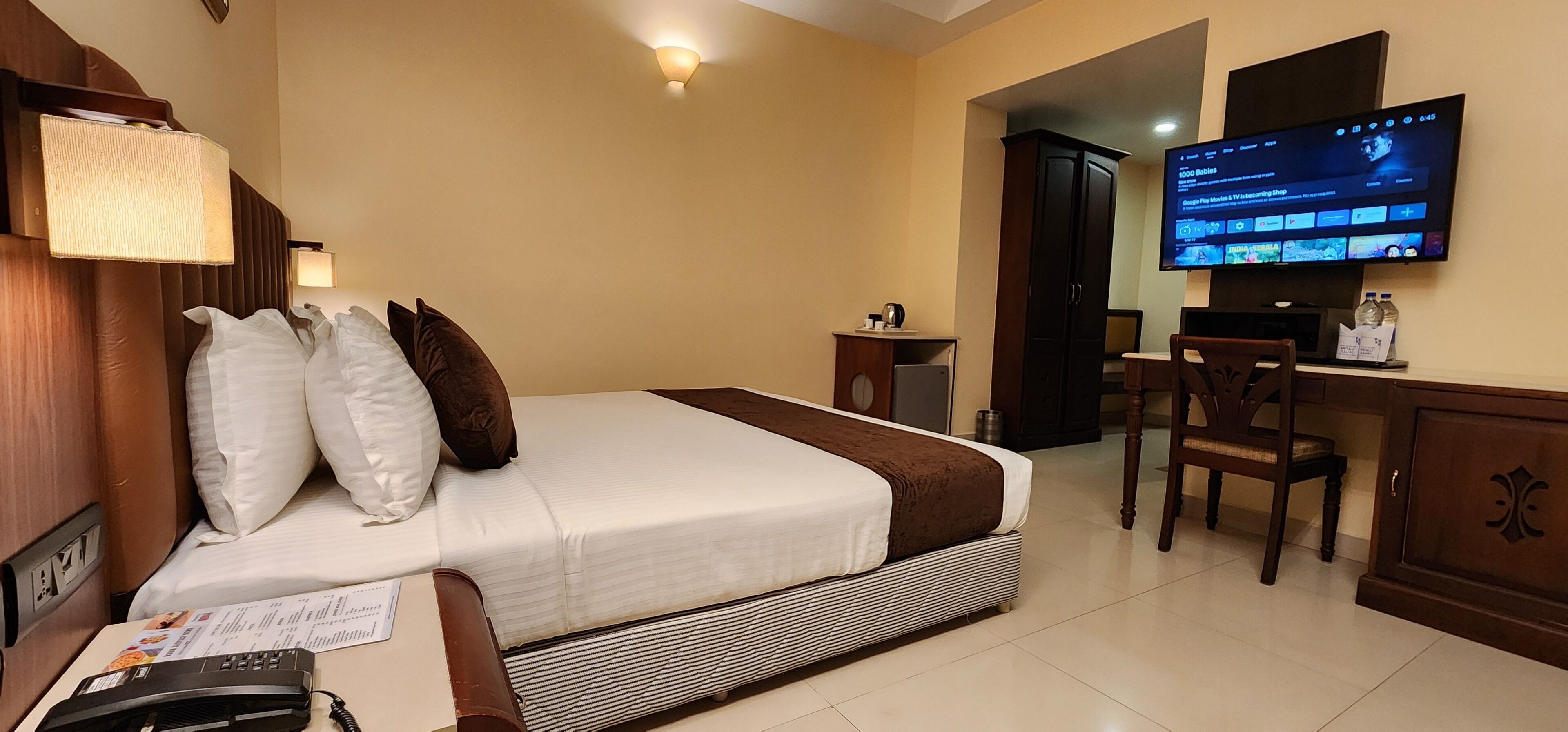 Une chambre d’hôtel équipée d’un lit, d’un bureau, d’une télévision et d’une armoire.