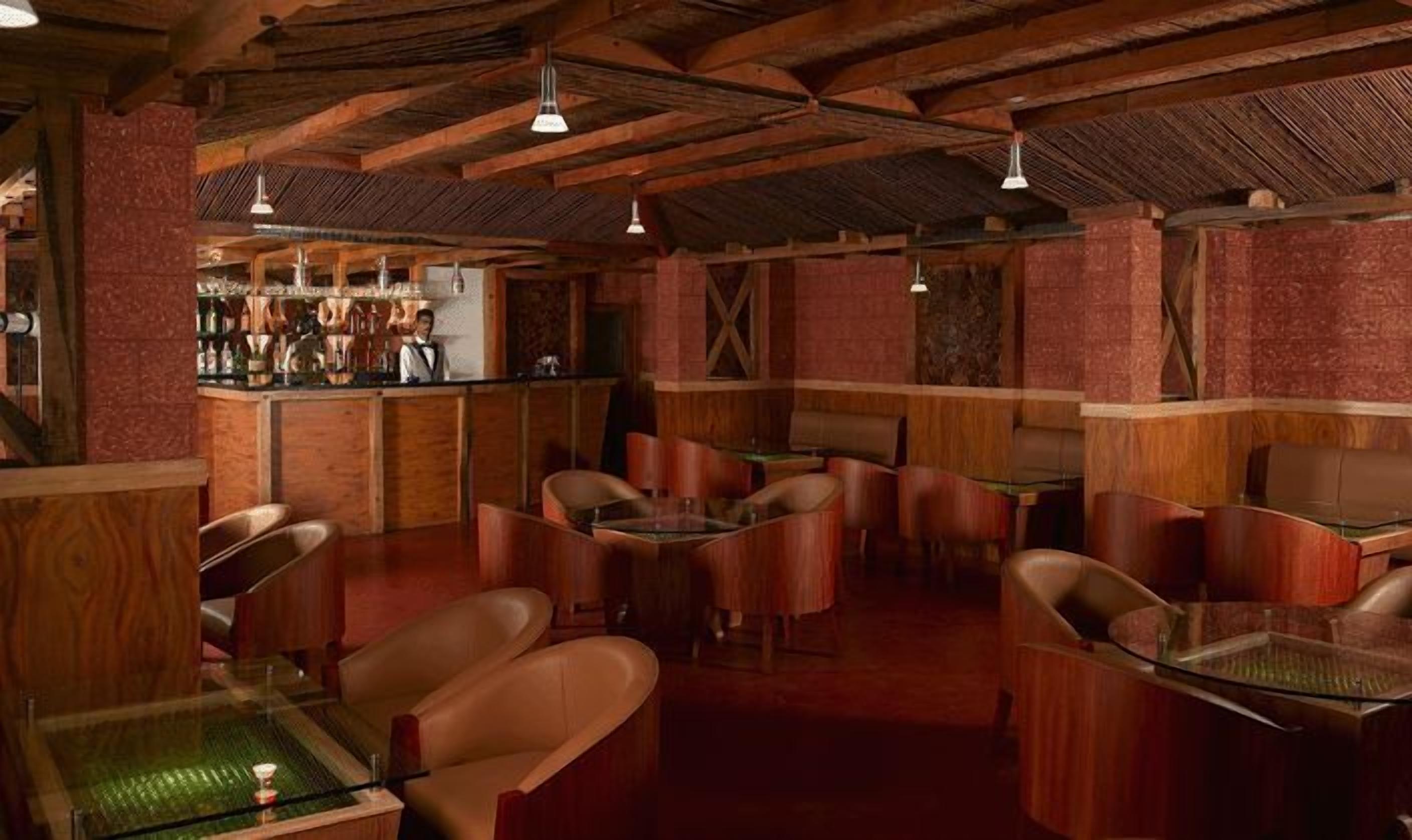 A rustic bar area with wooden beams, leather booths, and a bar counter with bottles.