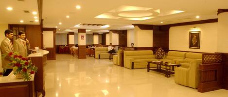 A hotel lobby with a reception desk, seating area, and a reception counter.