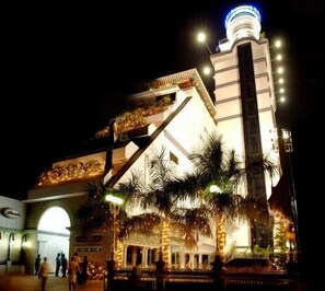 A large, illuminated building with a prominent tower and arched entrance. - Hotel Arcadia (Kottayam)