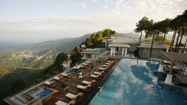 A rooftop infinity pool with wooden deck and lounge chairs, overlooking a mountainous landscape. - Moksha Himalaya Spa Resort (Kasauli)