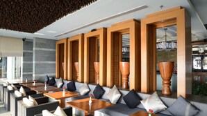 A modern indoor seating area with sofas, tables, and wicker chairs. - Moksha Himalaya Spa Resort (Kasauli)