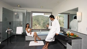 A modern bathroom with a glass shower enclosure, a bathtub, and a large mirror reflecting a scenic view. - Moksha Himalaya Spa Resort (Kasauli)