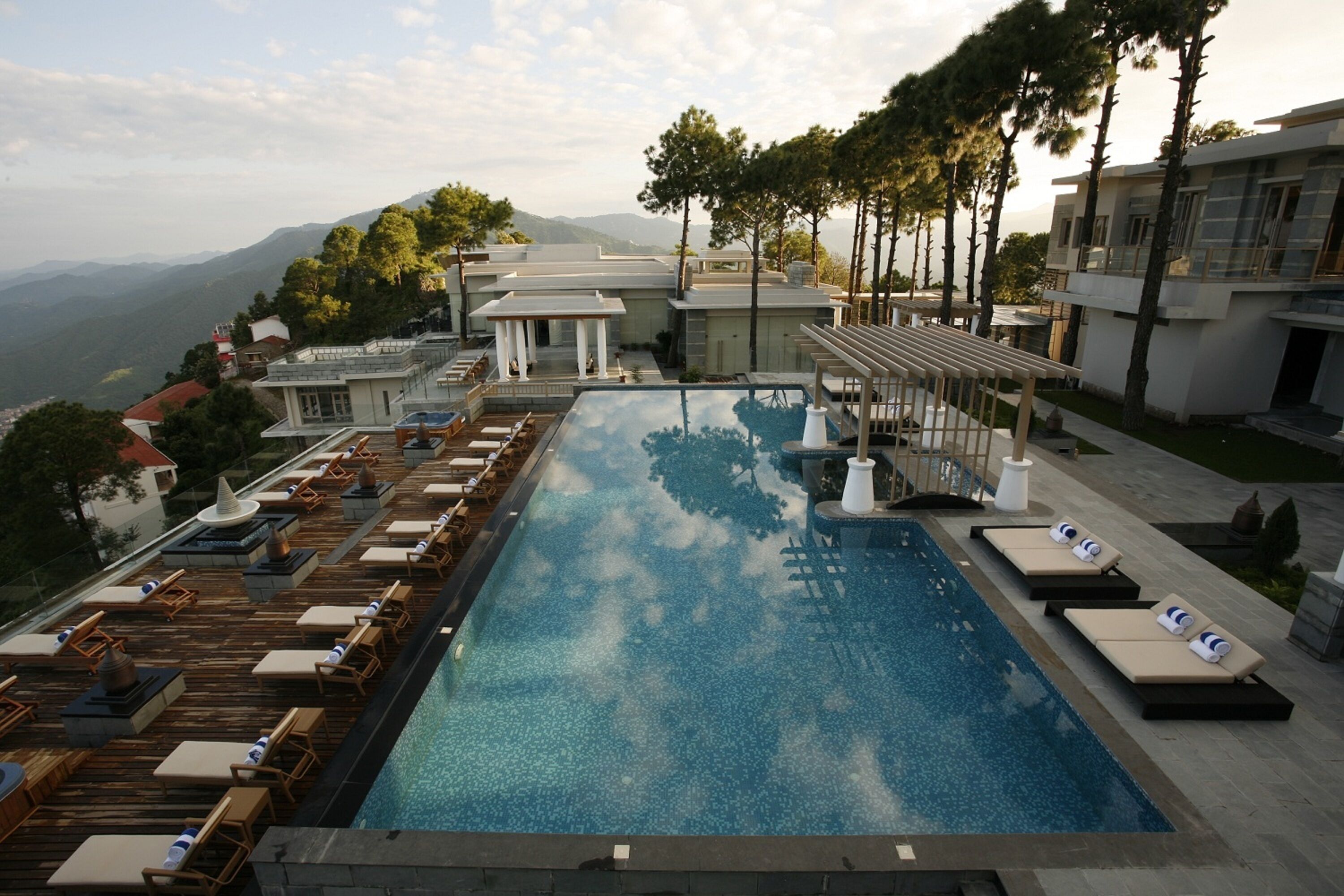 A rooftop infinity pool with lounge chairs and a view of the mountains.