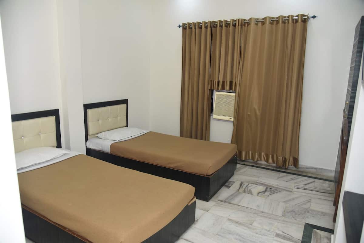 A hotel room with two beds, a window with curtains, and a tiled floor.