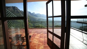 A balcony with a view of mountains, a chair, and a table. - Ayur County (Devikolam)
