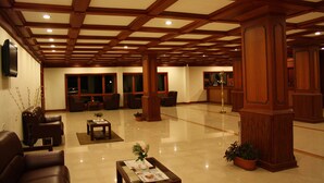 A spacious lobby with wooden beams, comfortable seating, and a reception desk. - Ayur County (Devikolam)