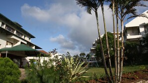 A hotel with multiple floors, a covered outdoor area, and a garden with palm trees. - Ayur County (Devikolam)