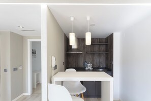 A modern kitchen with a white countertop, two pendant lights, and a wooden backsplash. - Flamingo Beach Resort (Benidorm)