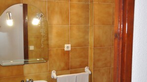 Un baño con lavabo, espejo e inodoro.