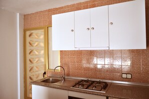 A kitchen with a gas stove, sink, and white cabinets. - Trebol One Apartments By Mc (Benidorm)