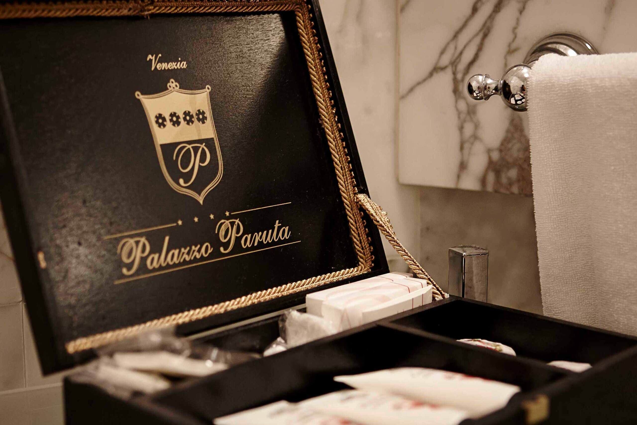 A black box with 'Palazzo Paruta' branding, a towel, and a marble wall in the background.