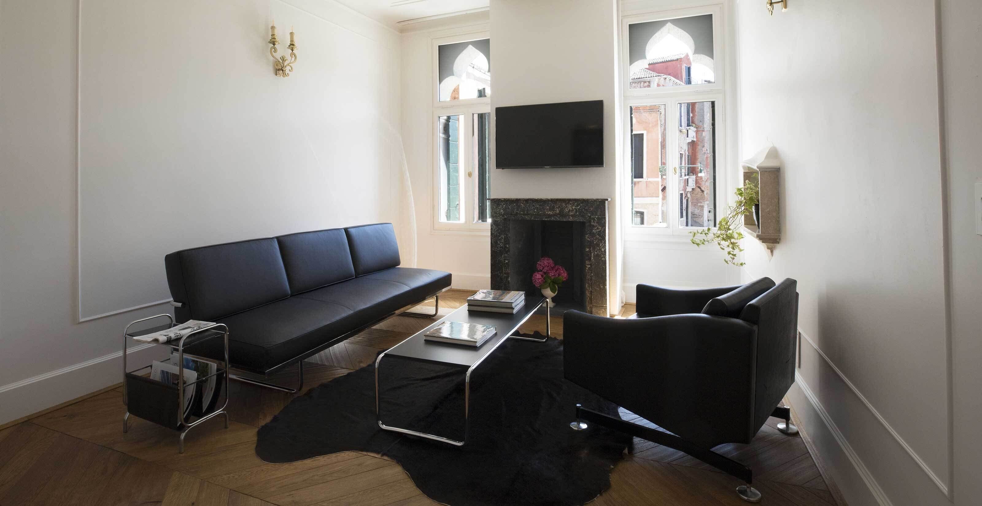 Una sala moderna con un sofá negro, una mesa de centro y una chimenea.