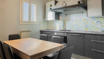 A kitchen with a dining table, chairs, a stove, oven, and a window.