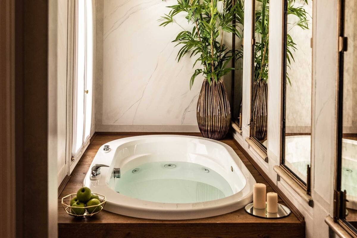 A spa room with a bathtub, a plant, and candles.