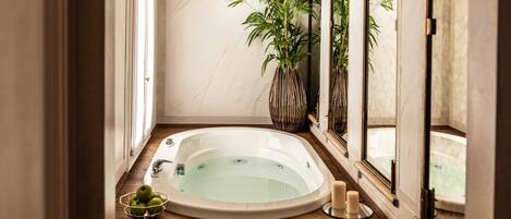 Ein Wellnessraum mit Badewanne, einer Pflanze und Kerzen.