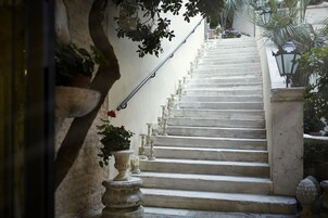 A staircase with a metal handrail, potted plants, and candles along the steps.