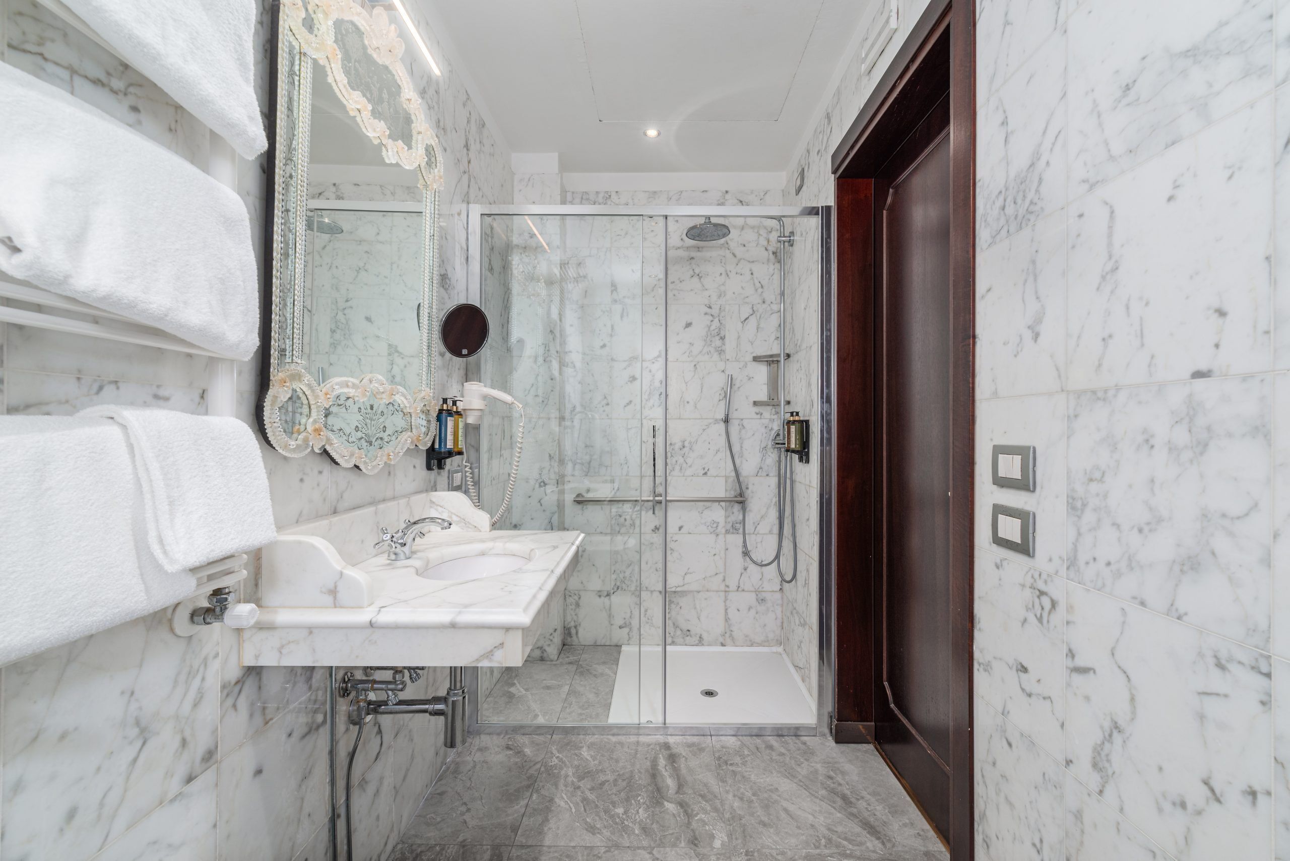 Un baño con ducha de mármol, lavamanos y espejo.