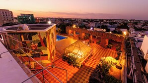 A rooftop terrace with a checkered floor, a glass greenhouse, and potted plants.