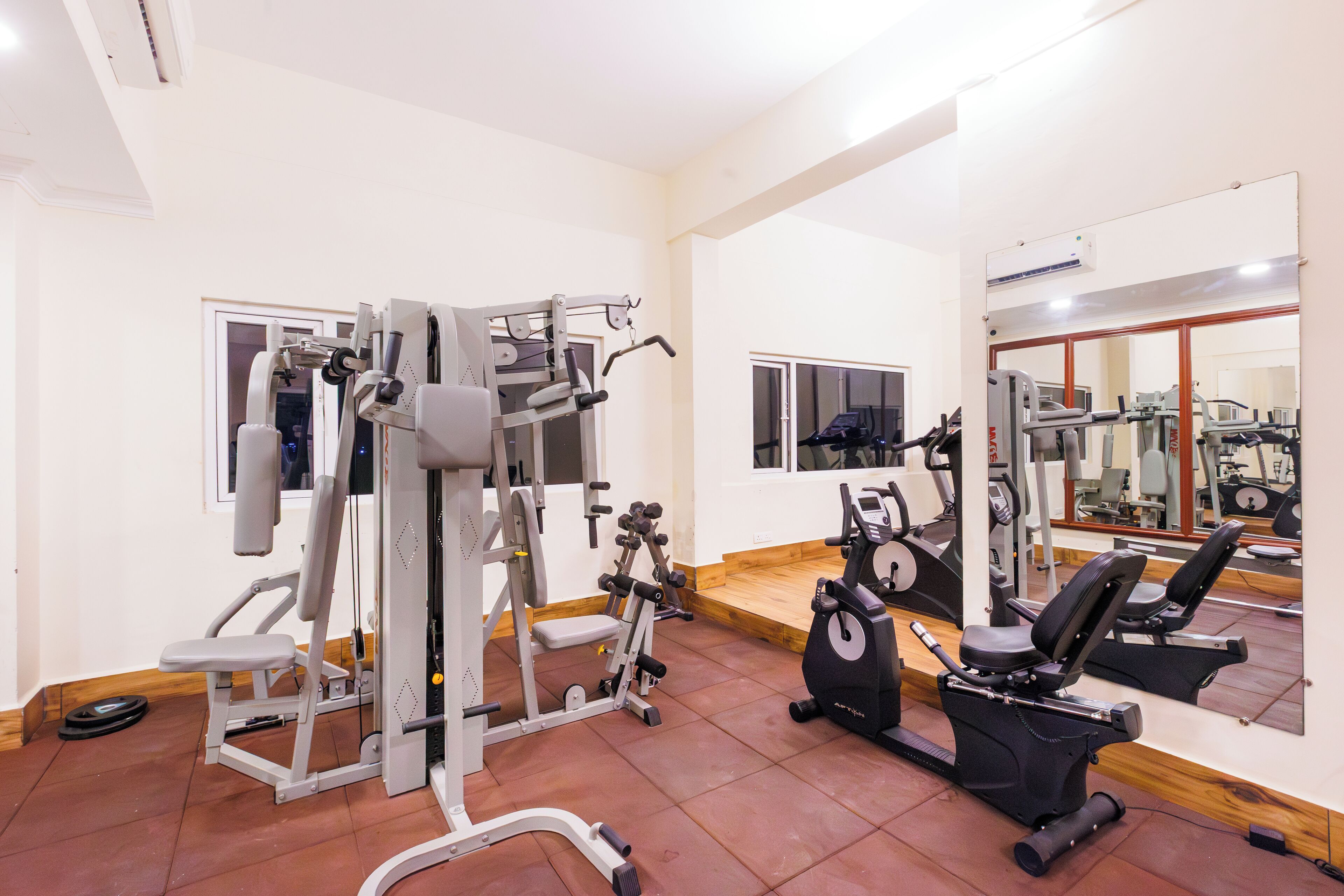Ein Fitnessstudio mit verschiedenen Trainingsgeräten, darunter ein Kraftgerät, Kurzhanteln und ein Crosstrainer.