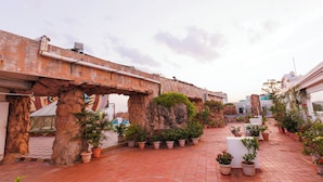 A courtyard with potted plants, a stone archway, and a tiled floor.