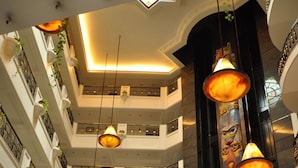 A multi-level hotel lobby with a central atrium, ornate columns, and a large tree.