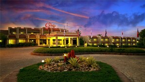 A hotel with a well-lit entrance, a landscaped garden, and multiple flags. - Clarks Khajuraho (Rajnagar)