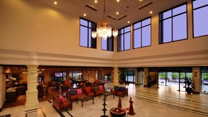 A spacious lobby with a chandelier, seating area, and large windows. - Clarks Khajuraho (Rajnagar)