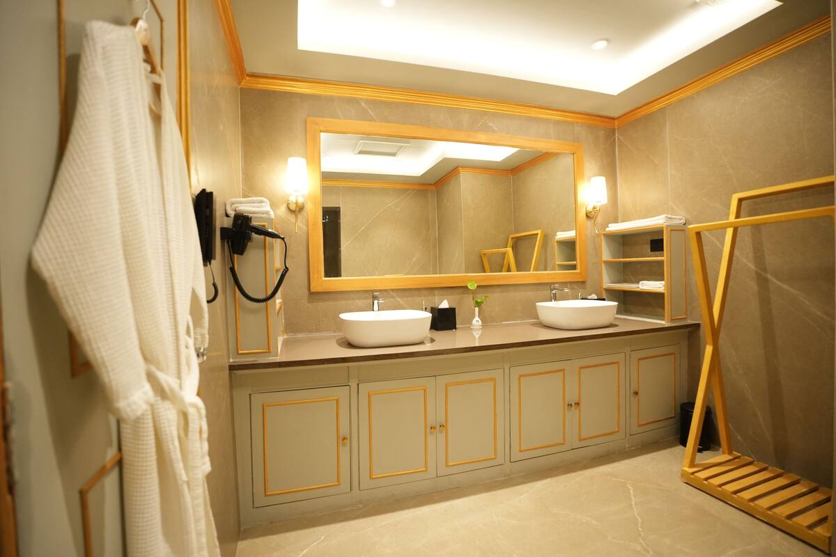 A modern bathroom with two sinks, a large mirror, and a towel rack.