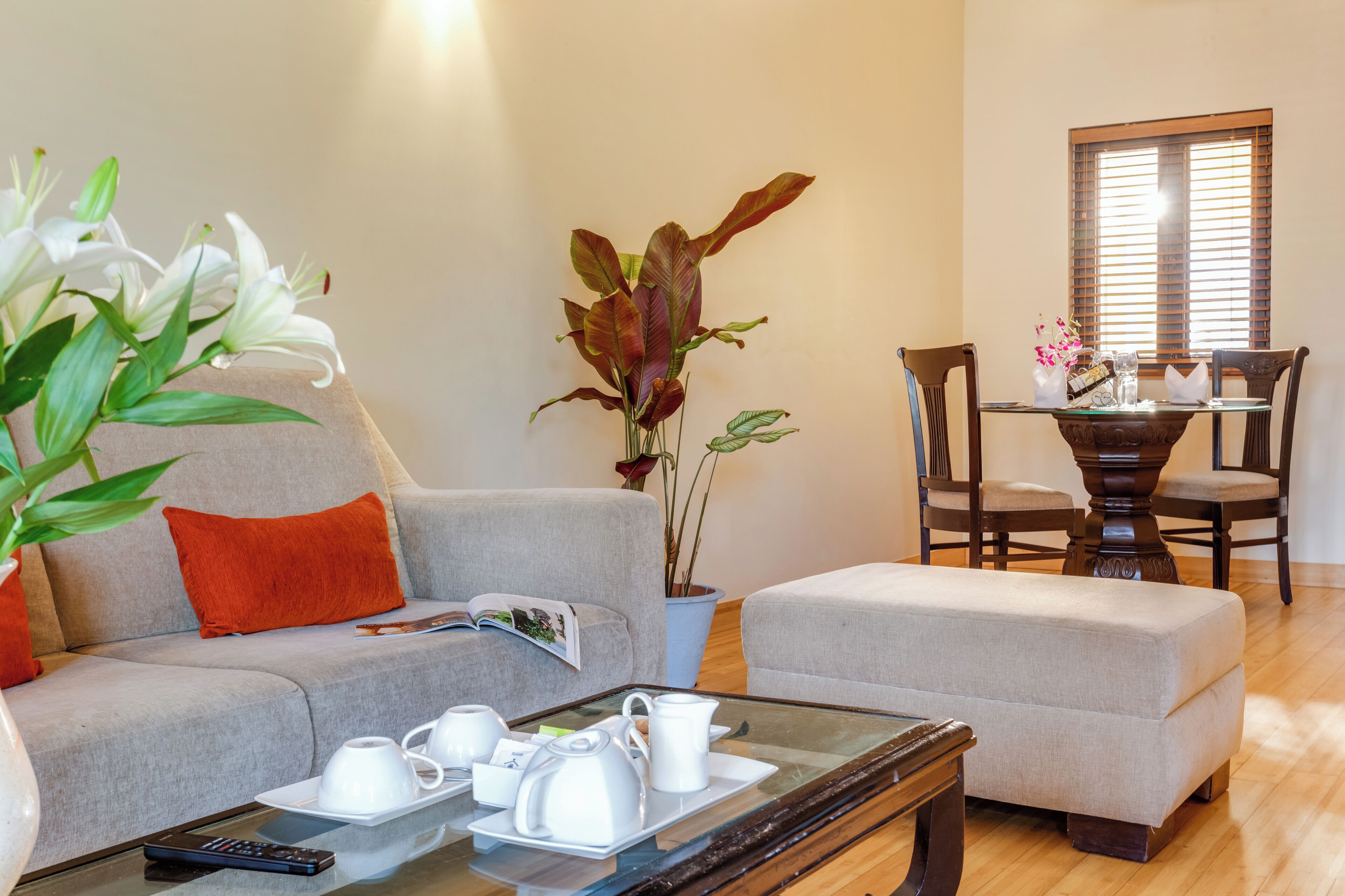 A living room with a sofa, ottoman, coffee table, and a dining area with a table and chairs.