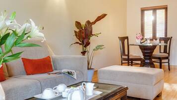 A living room with a sofa, ottoman, coffee table, and a dining area with a table and chairs.