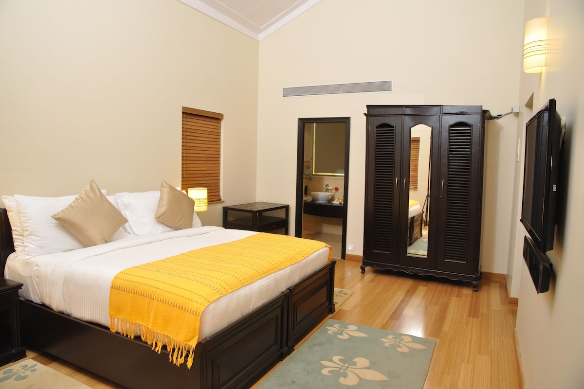 Quarto com cama, mesas de cabeceira, espelho e guarda-roupa.