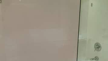 Un baño moderno con bañera de hidromasaje con mampara de vidrio, cabina de ducha con mampara de vidrio y un perchero con una toalla doblada.