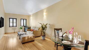 A spacious living area with a dining table, sofa, and a kitchen area in the background.