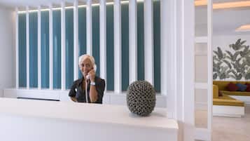A reception area with a modern design, featuring a white reception desk, a decorative spherical object, and a seating area with cushions.