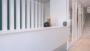 Una moderna zona de recepción con un mostrador blanco, una escalera y un suelo con diseño.