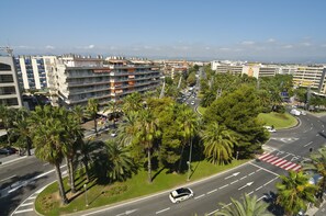 Un hôtel à plusieurs étages doté de balcons, d’une cour intérieure agrémentée de palmiers et offrant une vue sur le paysage urbain.