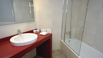 A bathroom with a white sink, red countertop, and a glass-enclosed shower.