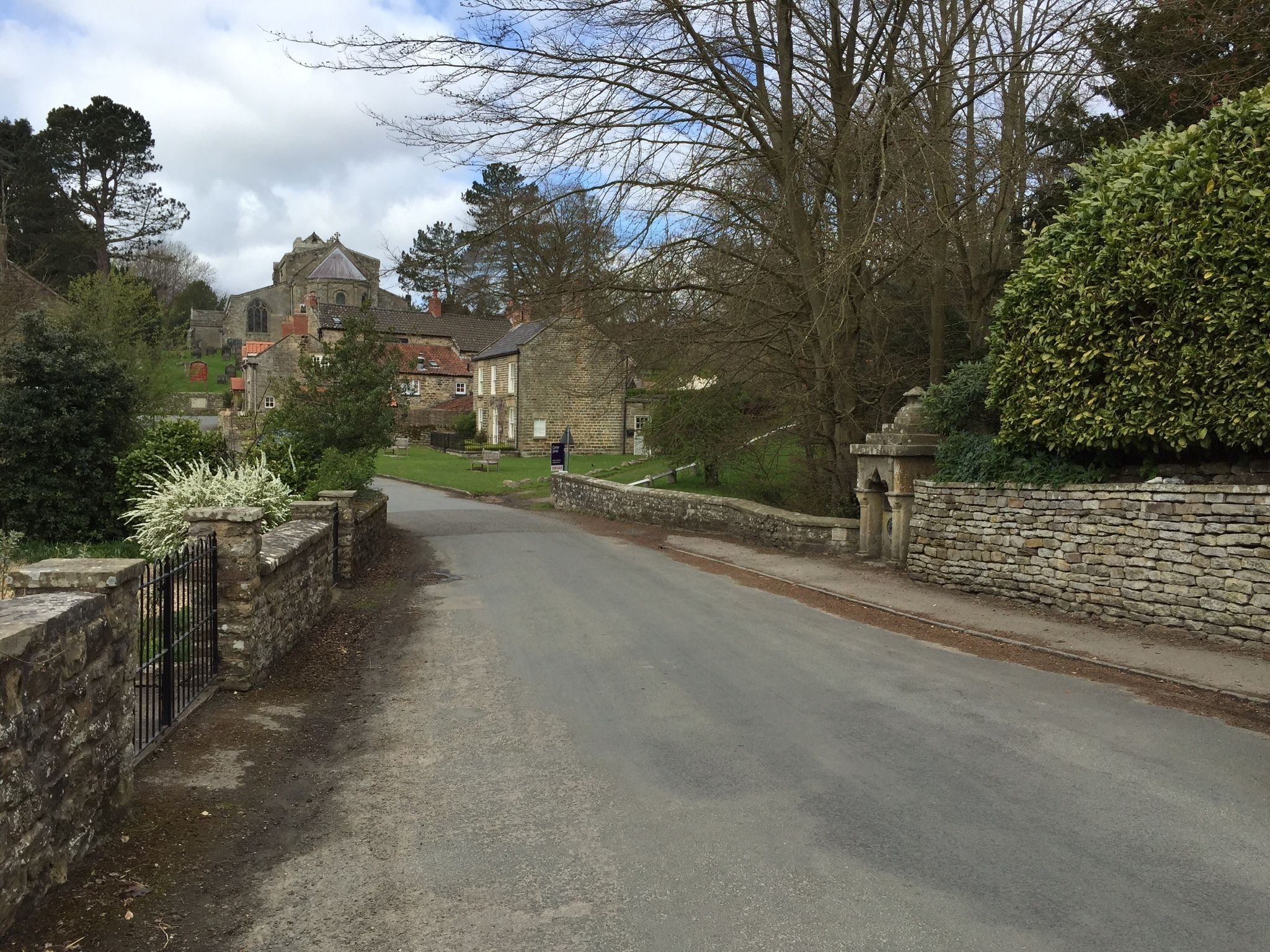 Une rue étroite bordée de murs de pierre et de bâtiments traditionnels, vraisemblablement située dans un village historique.