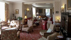 A spacious living room with multiple seating options, including armchairs and a sofa, arranged around a central area with a piano. - Lastingham Grange (York)