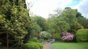 A garden pathway with neatly trimmed hedges and a variety of shrubs. - Lastingham Grange (York)