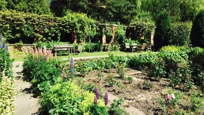 A garden with a pergola, seating area, and various plants. - Lastingham Grange (York)