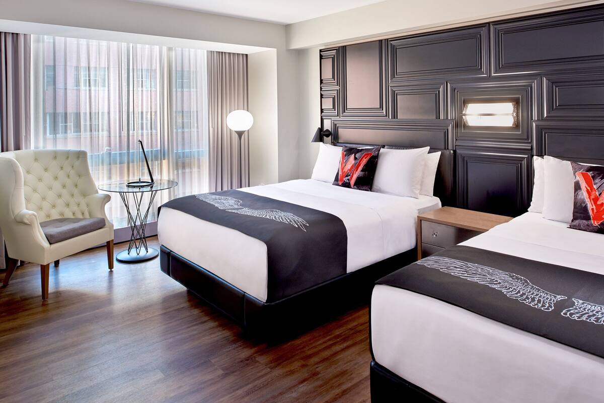 Een hotelkamer met twee bedden, een stoel, een tafeltje en een lamp.