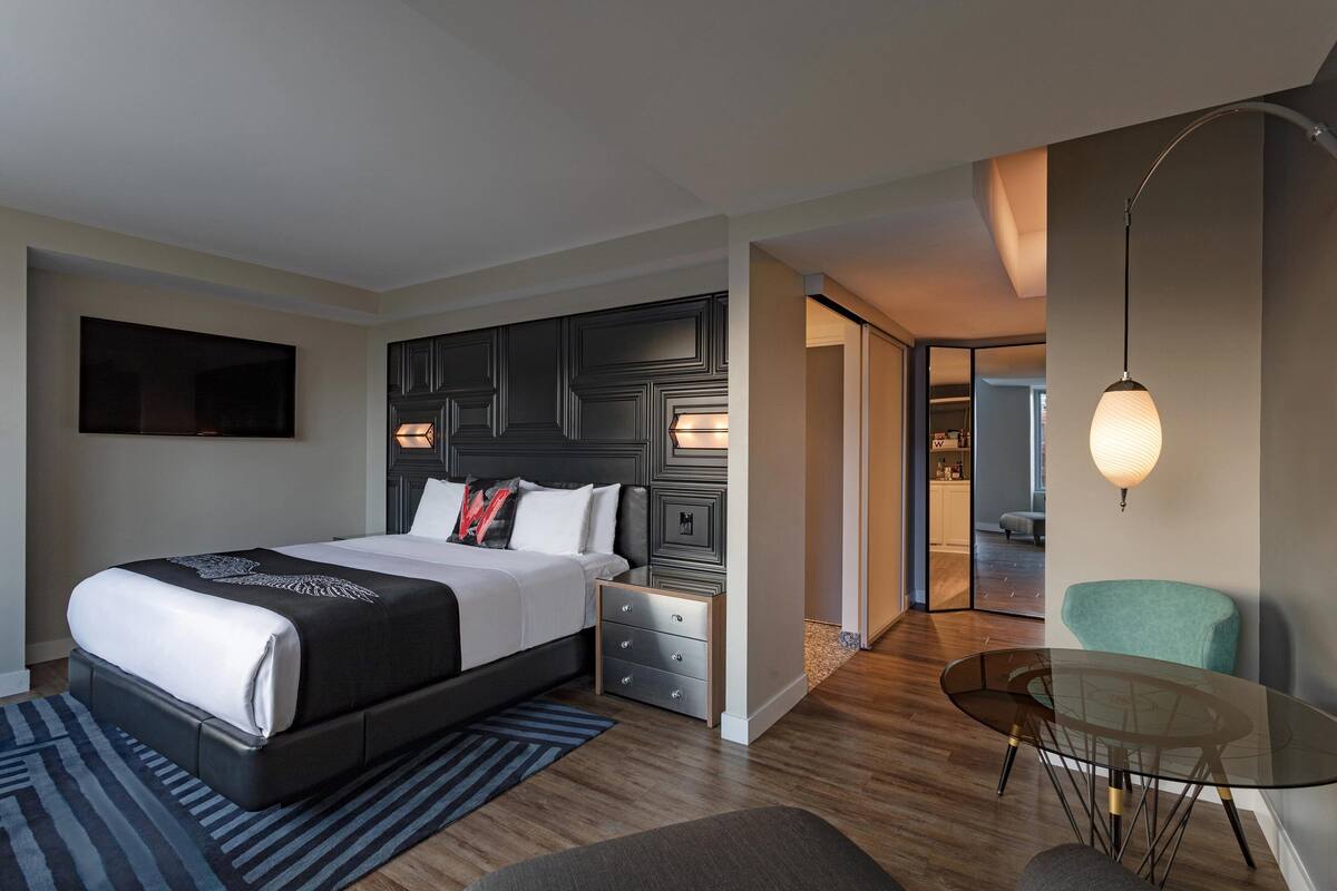 Een moderne hotelkamer met een groot bed, nachtkastjes, een glazen tafel en een zithoek.